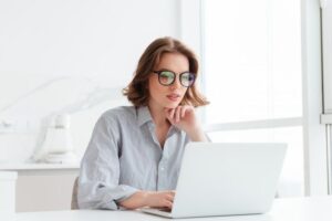 femme qui travaille sur un ordinateur avec des lunettes pour protéger les yeux de la lumière bleue
